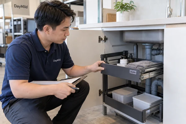 Asian employee illustration reviewing DayMild under sink organizers samples